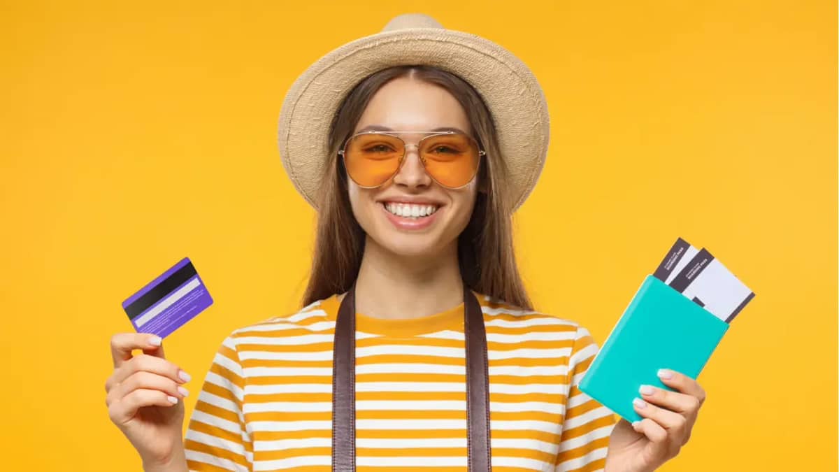 Turista segurando cartão de crédito e passagens aéreas